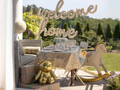 Auksinis meškučio balionas ant dovanos šalia supamo arkliuko ir užrašo „Welcome home"