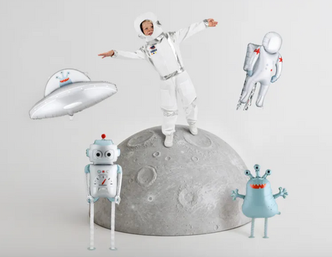 Sidabrinis NSO balionas kosmoso dekoracijose su astronauto kostiumu vilkinčiu vaiku, roboto, ateivio ir astronauto balionais.